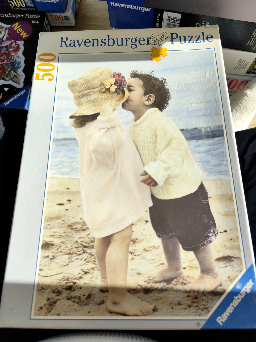 A young girl and boy sharing a tender moment on a sandy beach.