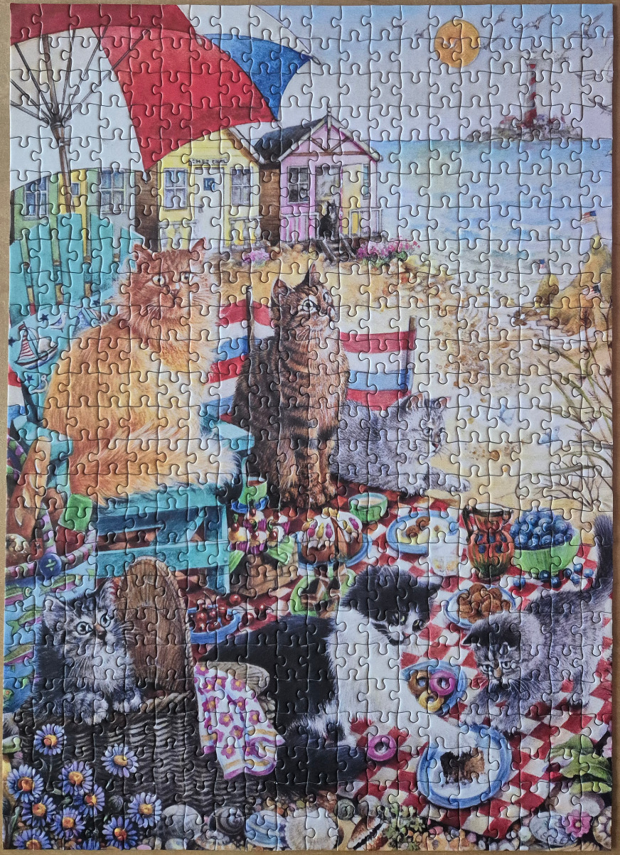 An illustration of several cats enjoying a picnic on a beach in front of colorful wooden beach huts.