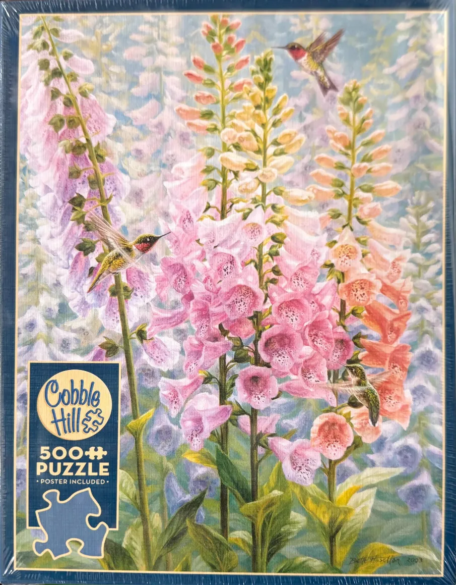 Three hummingbirds hovering around tall, vibrant stalks of pink, yellow, and peach foxglove flowers.