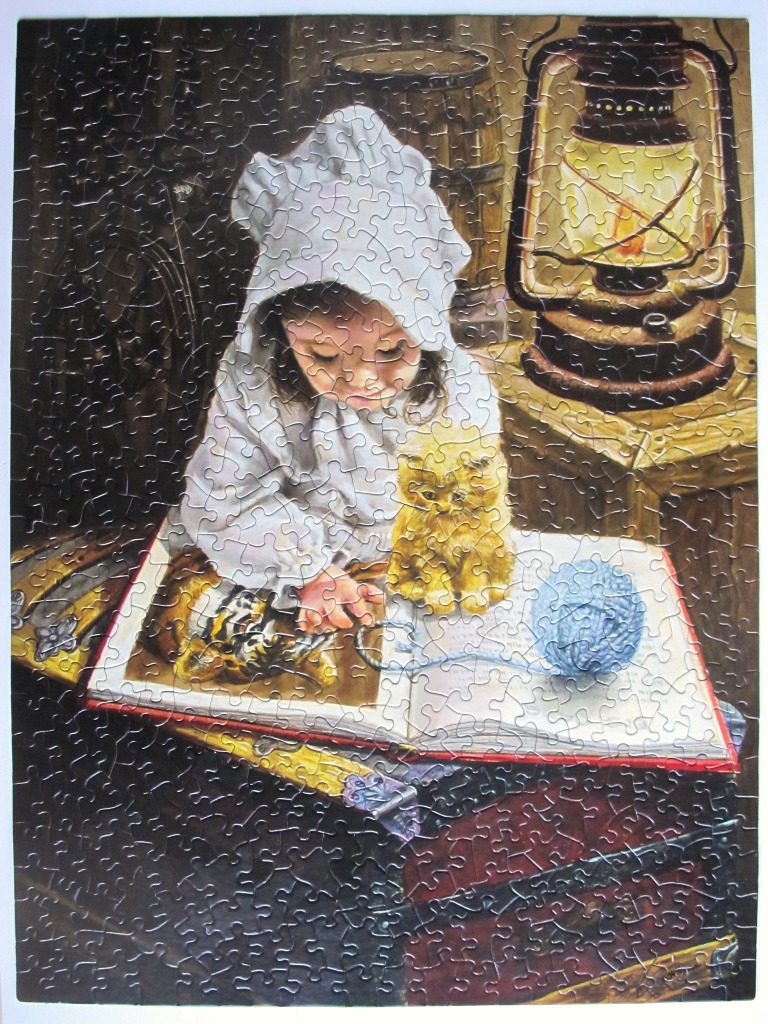 A young child in a white nightcap sits reading a book by lantern light with a small kitten nearby.