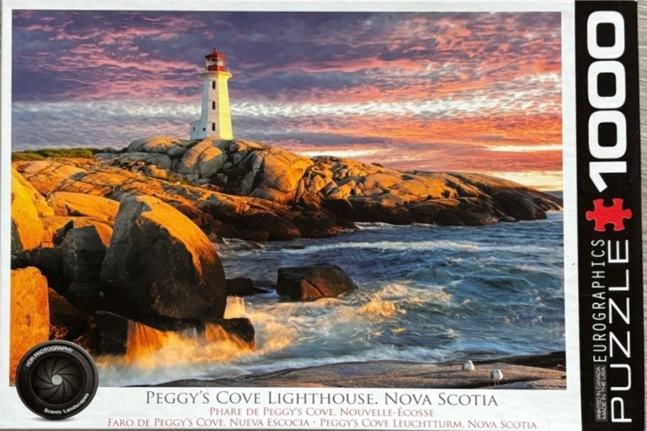 Peggy's Cove Lighthouse in Nova Scotia at sunset, featuring a white tower on rocky shores with a vivid orange sky.