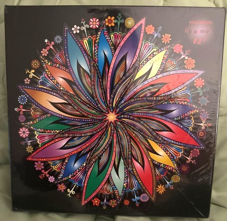 A colorful, symmetrical mandala illustration featuring intricate floral-like petals against a solid black background.