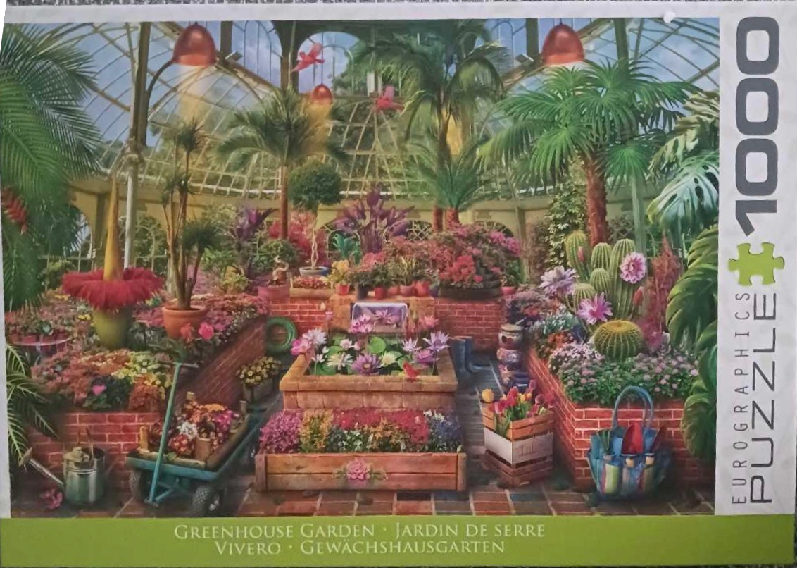 An indoor greenhouse filled with various exotic plants, brick planters, and a small water fountain.