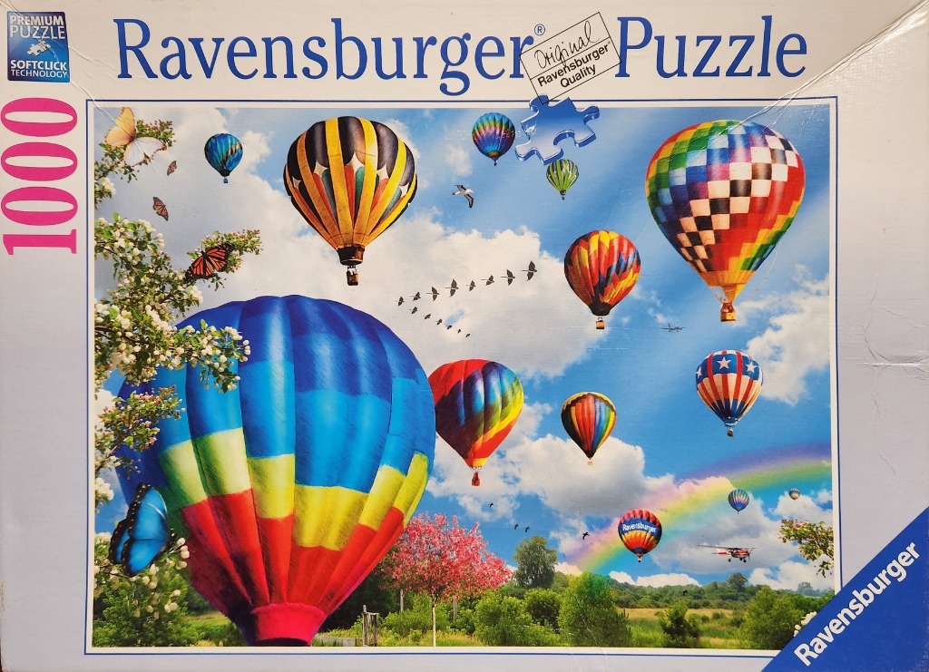 A collection of colorful hot air balloons floating in a bright blue sky above a lush green landscape with a rainbow.