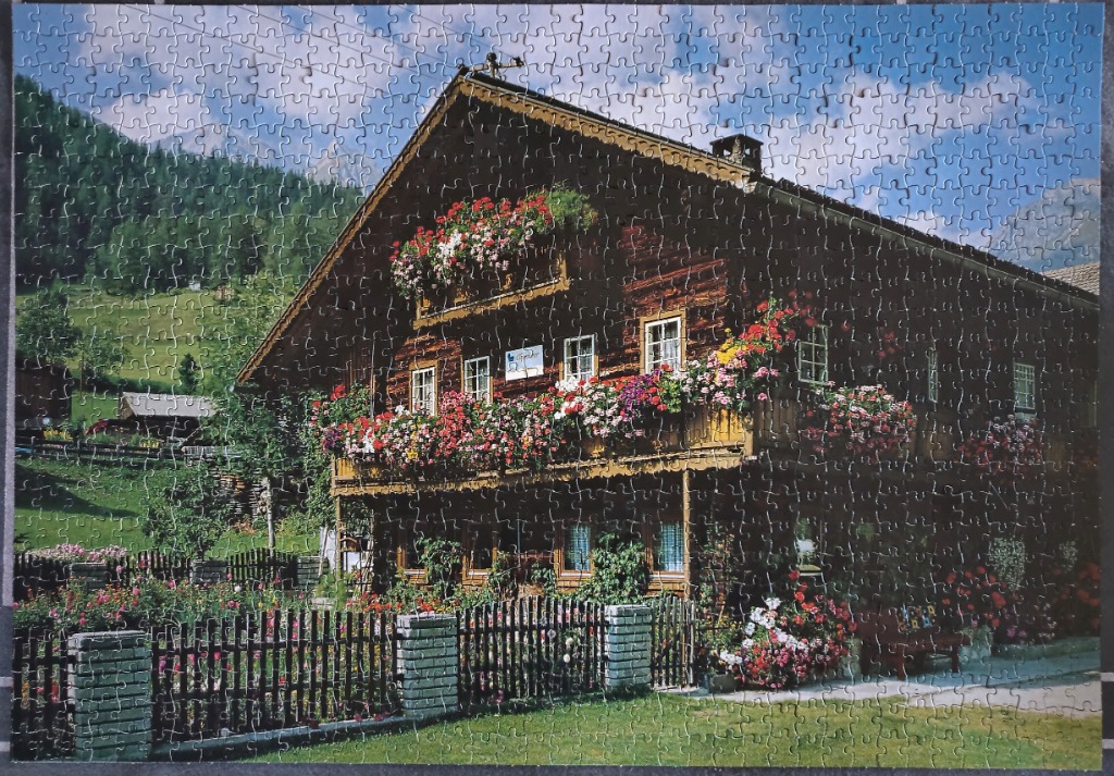 Traditional timber-framed chalet nestled in a lush alpine meadow with vibrant flower-filled balconies.