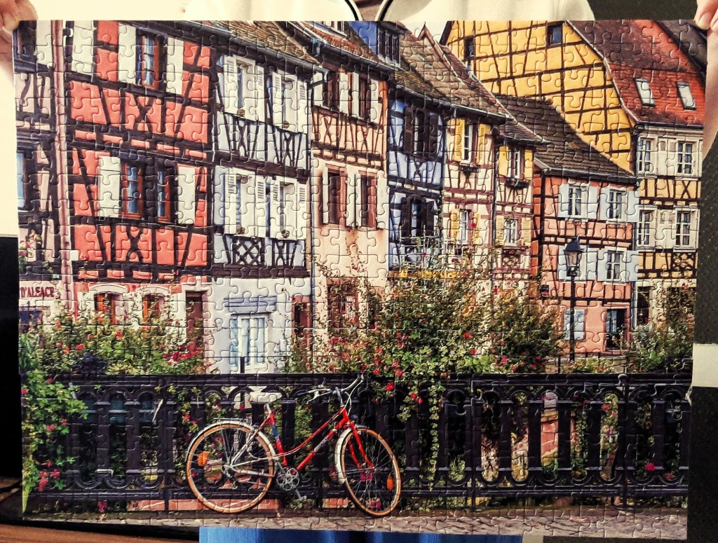 A row of colorful half-timbered houses with a red bicycle parked in front of a metal fence.