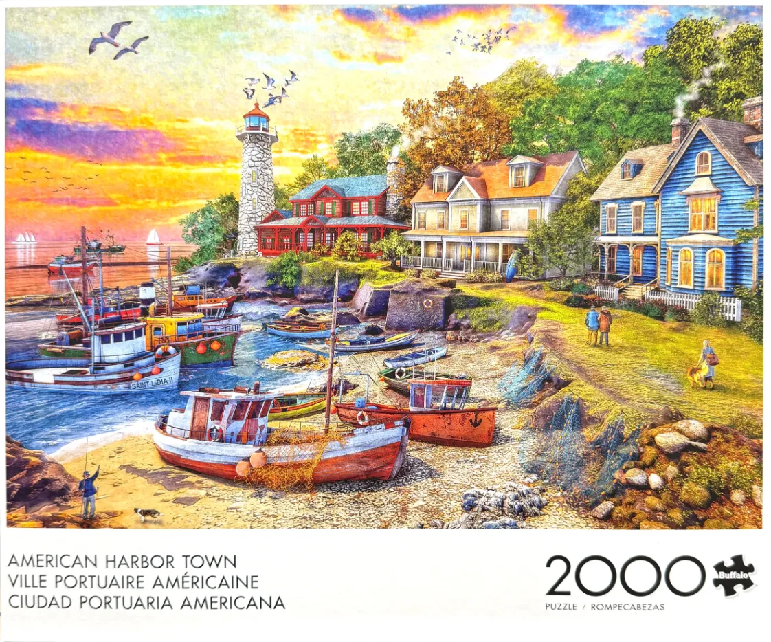 Coastal town scene at sunset featuring a lighthouse, colorful fishing boats, and houses.