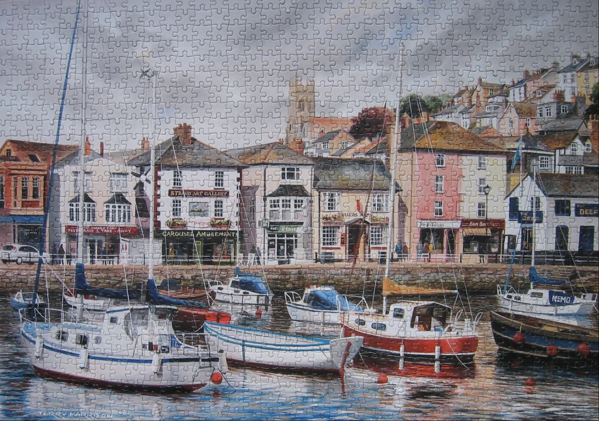 Watercolour painting of boats moored in a harbour before a hillside town with shops and a church tower.