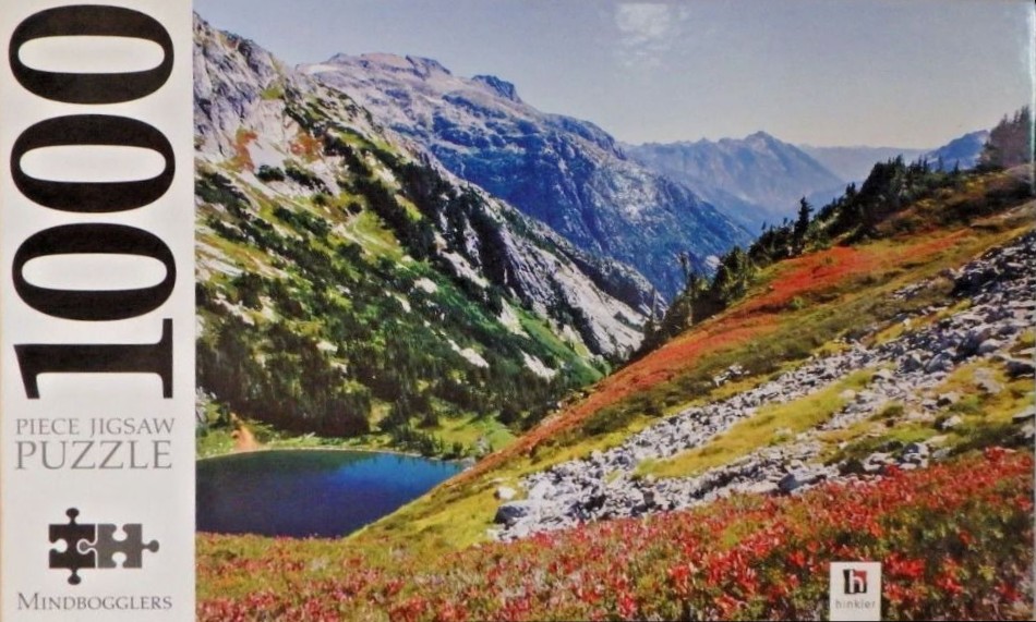 A scenic photograph of a deep blue alpine lake nestled between mountain slopes covered in rocky terrain and autumn foliage.
