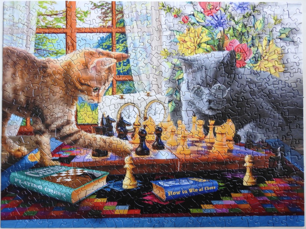 An orange tabby cat and a grey cat playing a game of chess on a table in a sunlit room.