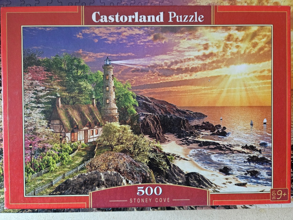 A lighthouse and thatched cottage overlooking a rocky coast at sunset.