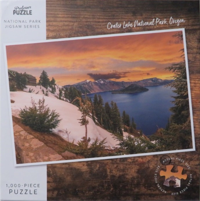 A photograph of Crater Lake National Park in Oregon at sunset, featuring snowy banks and a distant island.