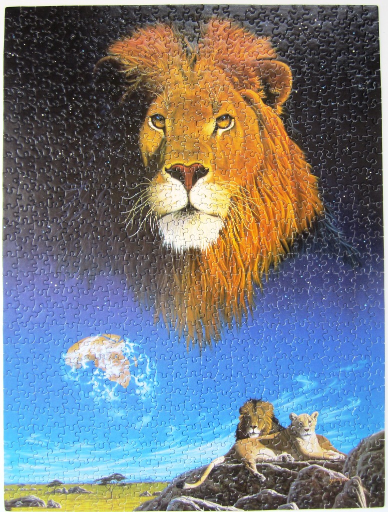 A majestic lion head floating in a star-filled night sky above a lion pair resting on a rocky savanna outcropping.