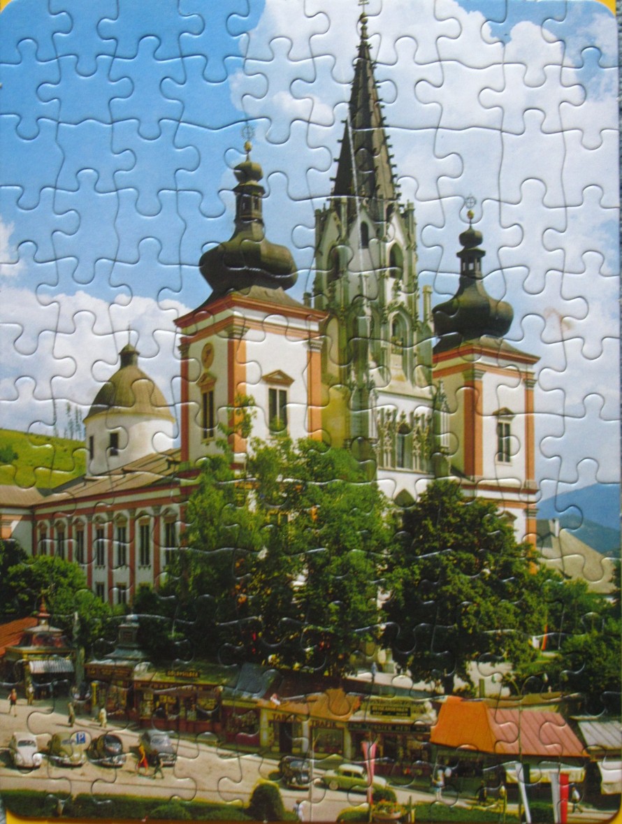 A view of the Mariazell Basilica in Austria with a town square and vintage cars in the foreground.