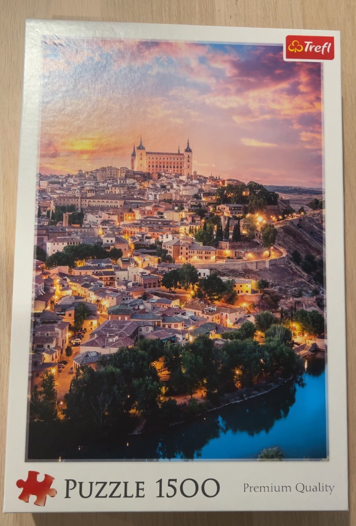 A panoramic view of the historic city of Toledo, Spain at sunset, featuring the Alcázar fortress overlooking the town.