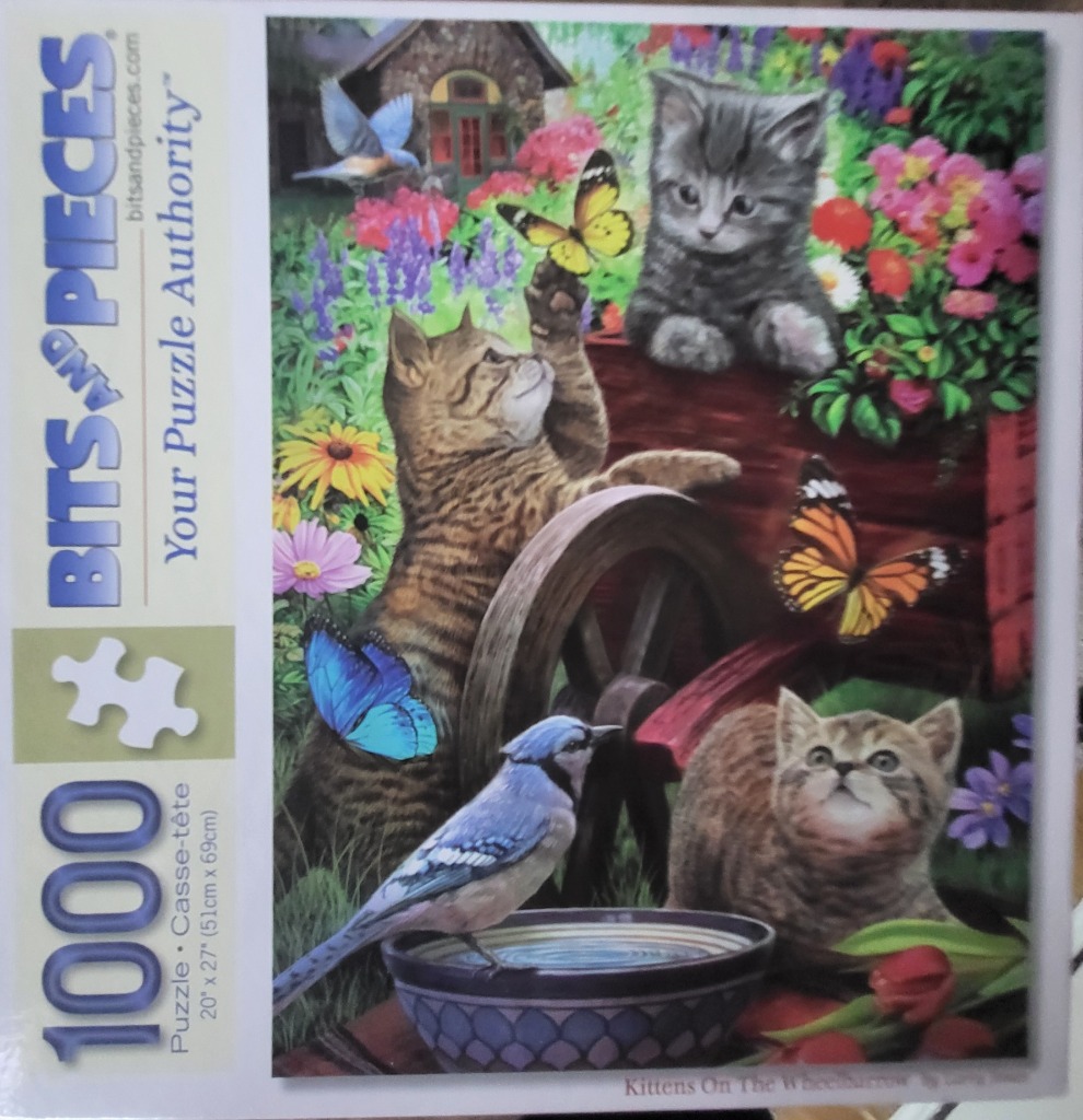 Three kittens playing around a wooden wheelbarrow in a lush garden with butterflies and a blue jay.