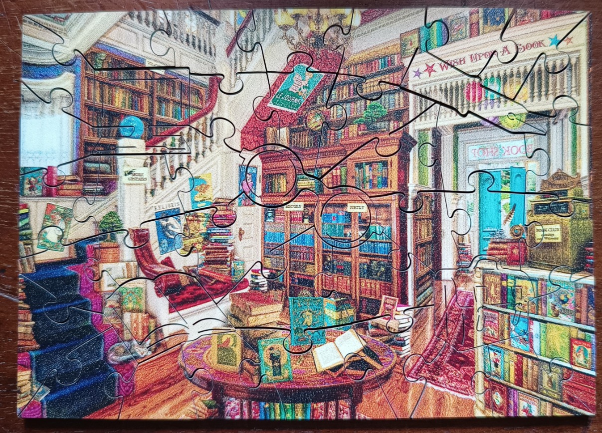 A cozy, illustrated interior scene of a multi-level bookshop filled with shelves, stairs, and a circular reading table.