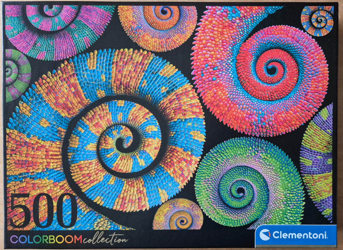Macro close-up of multiple curled chameleon tails in vibrant, iridescent colors against a black background.