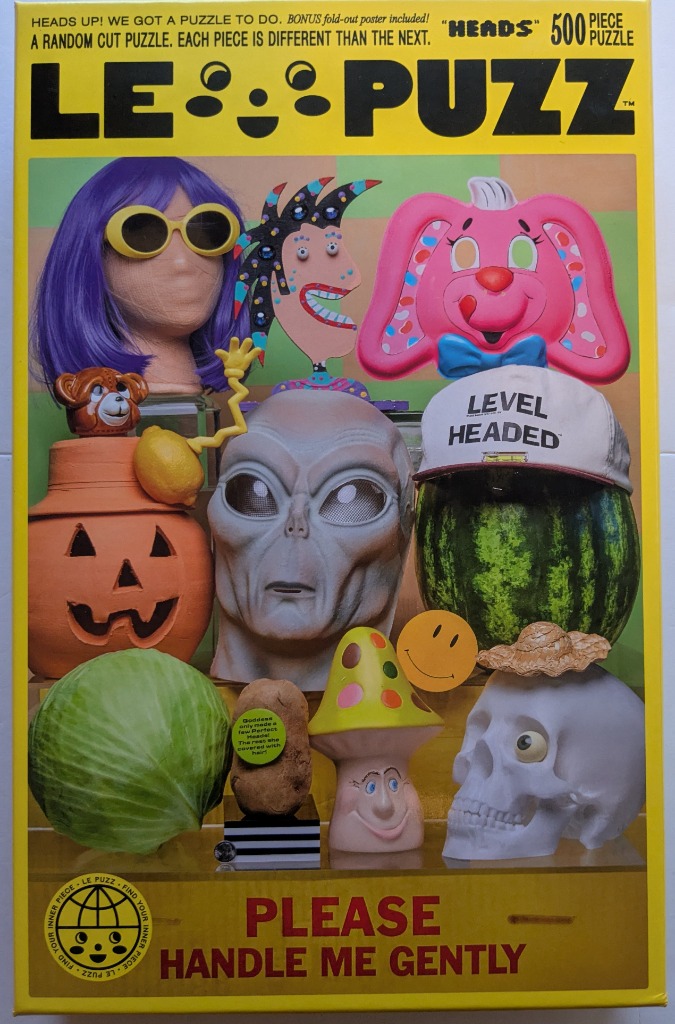 A whimsical collection of various heads, masks, and objects arranged in a grid-like display against a light green background.