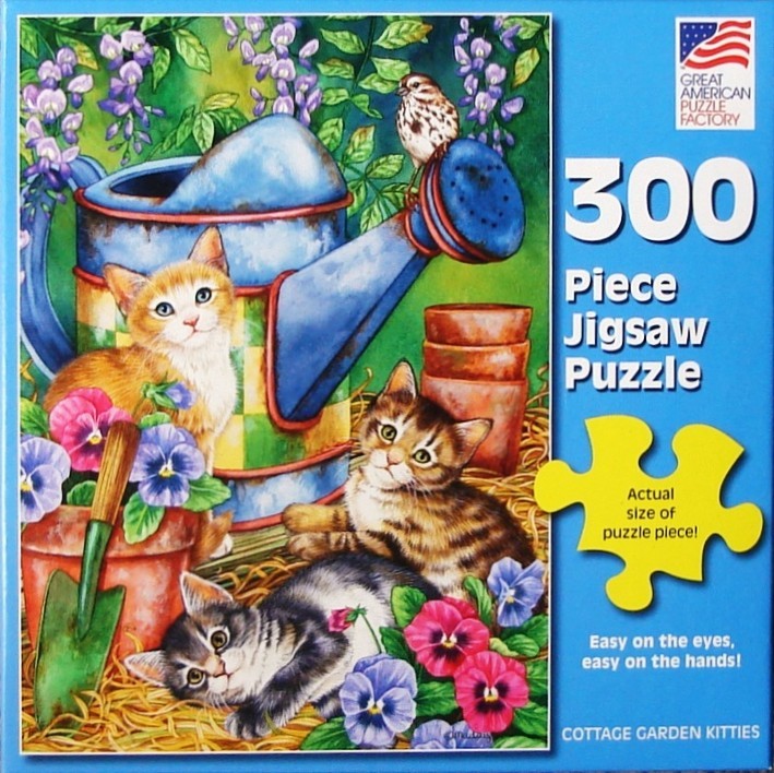 Three kittens playing in a garden next to a blue watering can surrounded by colorful pansies.