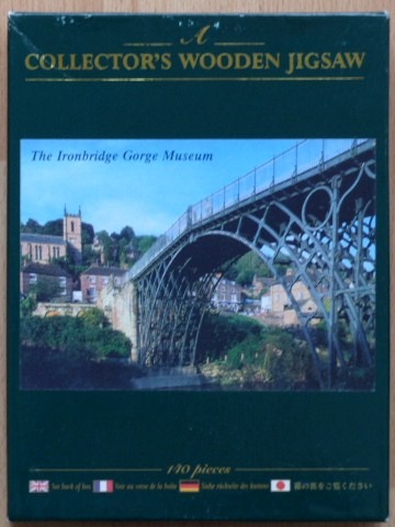 Photograph of the historic Ironbridge, with the village and church visible in the background under a blue sky.