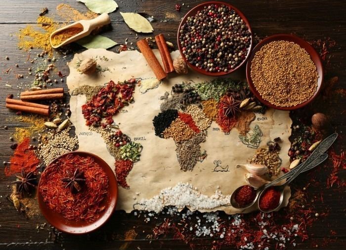 A world map created using various colorful culinary spices and herbs on a weathered parchment background.