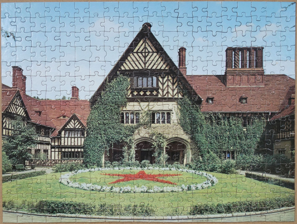 A Tudor-style manor house with a star-shaped floral design in the front garden.