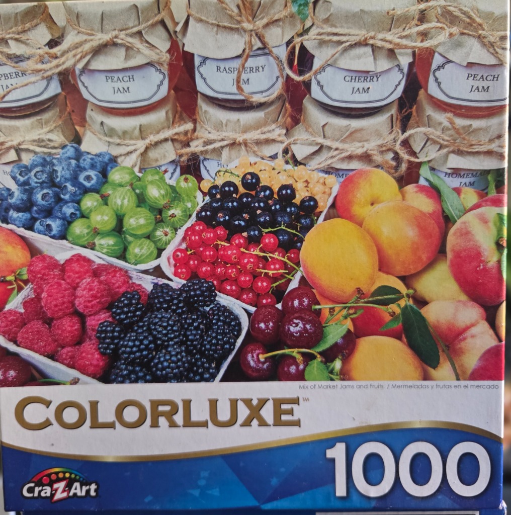 An assortment of fresh berries, fruits, and homemade jam jars with rustic brown paper lids and twine.