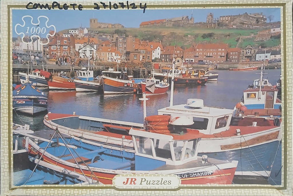 A bustling harbour filled with colourful fishing boats in front of a hillside town in Whitby, England.
