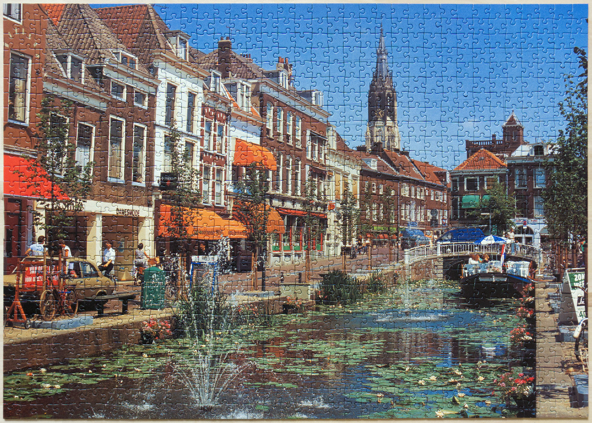 A sunny day at a canal in a historic Dutch town with a tall church spire in the background.