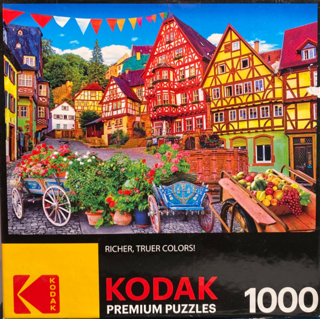 A charming town square in Germany featuring half-timbered houses, flower-filled carts, and colorful bunting.