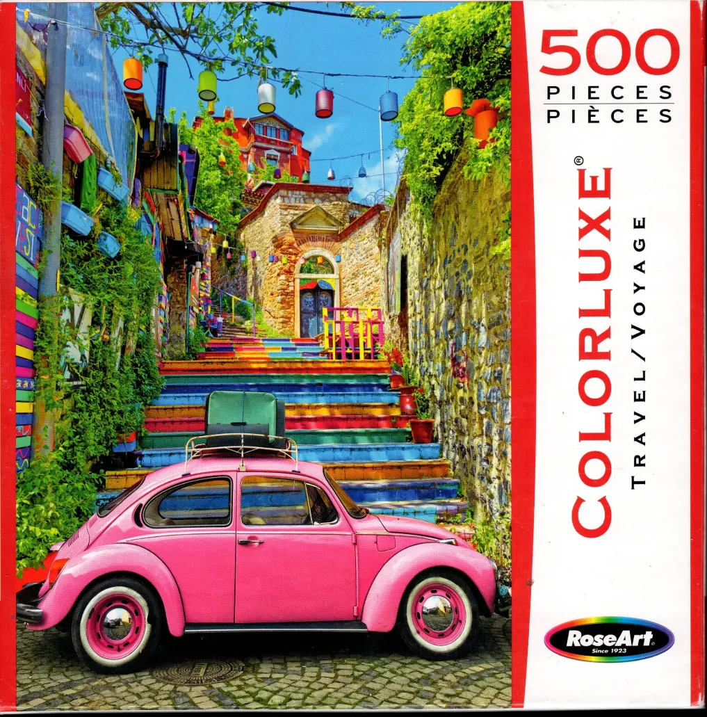 A vibrant pink vintage car parked at the bottom of a set of rainbow-painted stone stairs in a European-style alleyway.