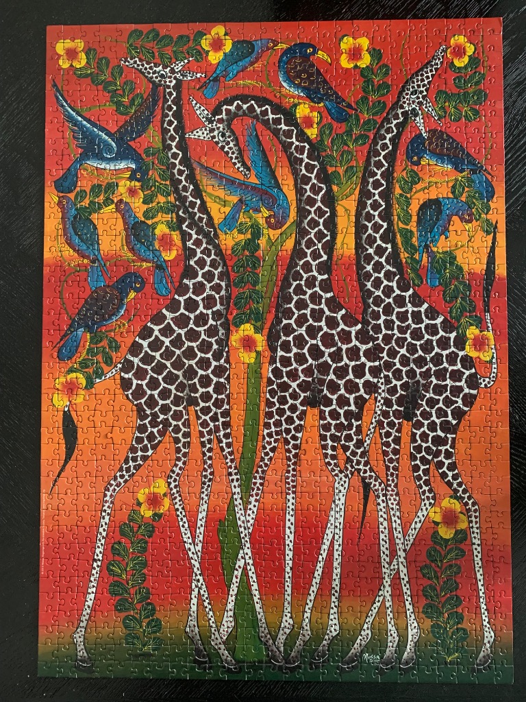 Three giraffes standing amidst tropical flowers and birds against a vibrant orange sunset background.