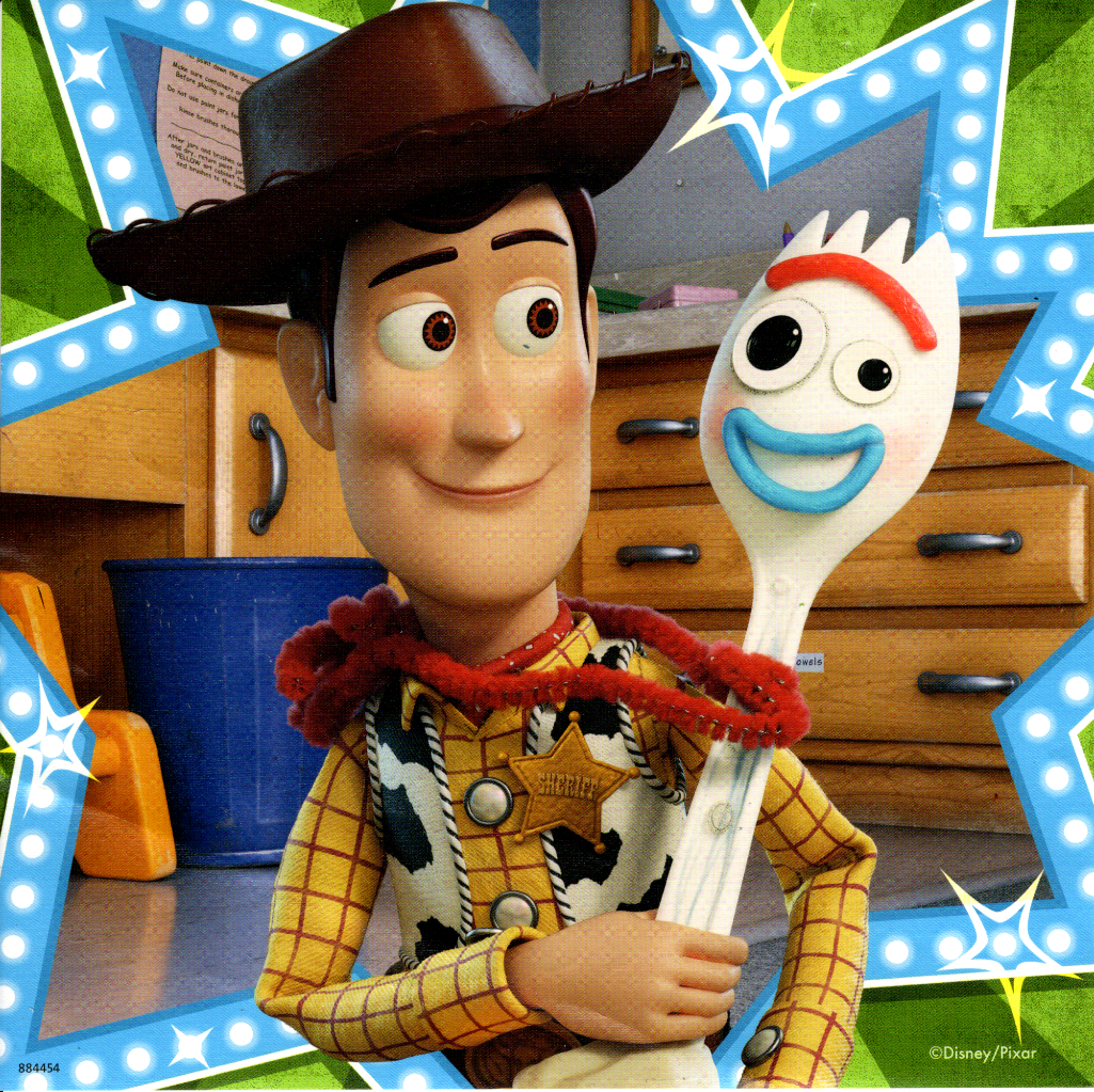 Woody the cowboy doll and a homemade spork character stand in front of a wooden cabinet.