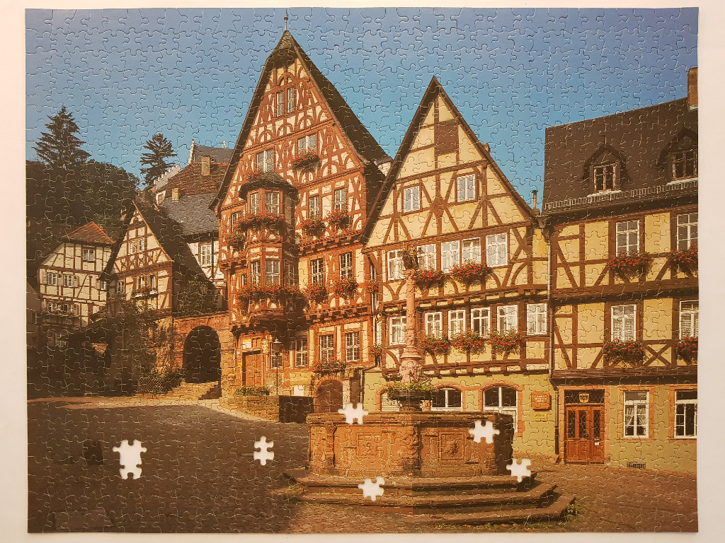 A sunny German town square with timber-framed buildings and a stone fountain.