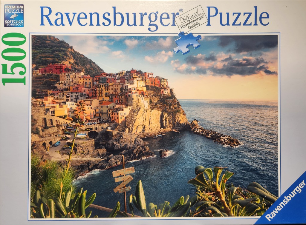 A photograph of the Italian coastal village of Manarola at sunset, featuring colorful houses on a rocky cliff.