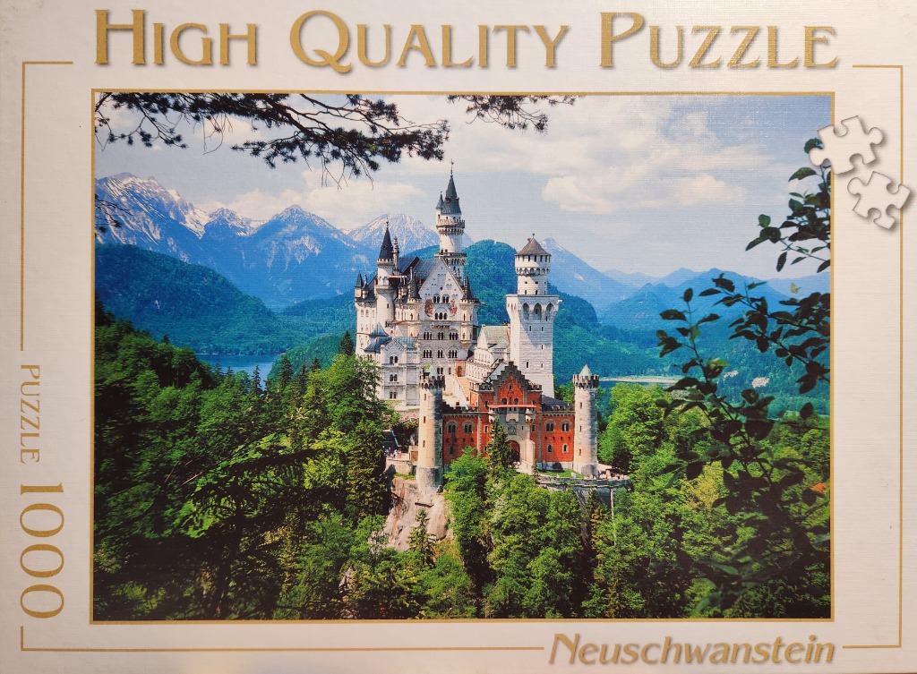 A scenic photograph of Neuschwanstein Castle surrounded by lush green forests and snow-capped mountains.