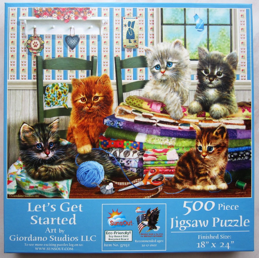 Four kittens of various colors playing around a stack of colorful quilts in a country-style room.
