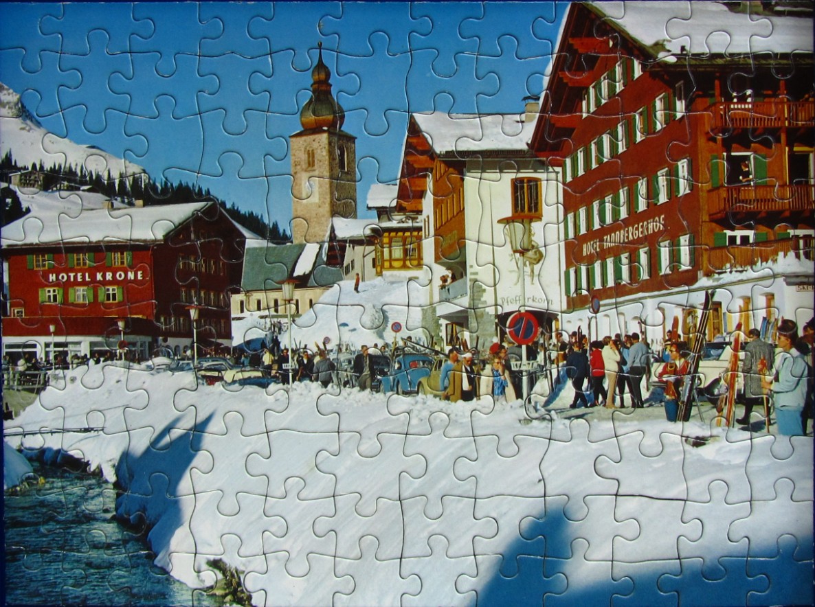 Winter scene in an Austrian village with red hotels, a church spire, and snow-covered streets.