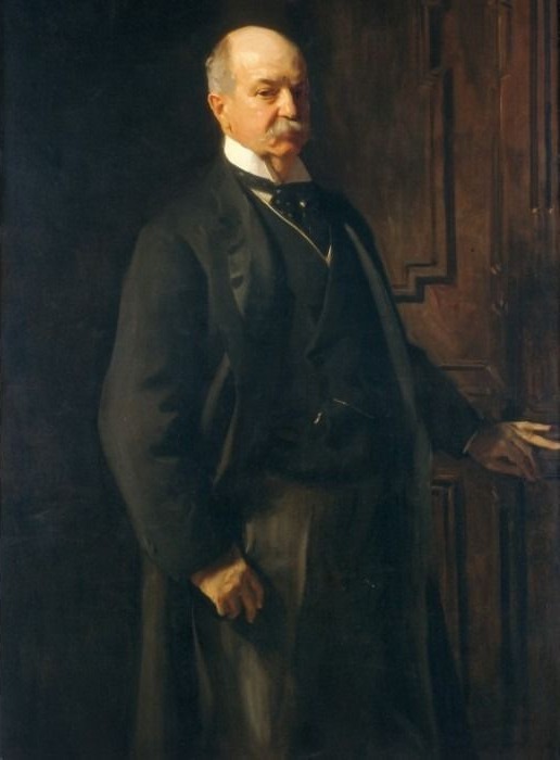 A formal, dimly lit portrait of an older gentleman with a mustache, wearing a dark suit against a wooden backdrop.