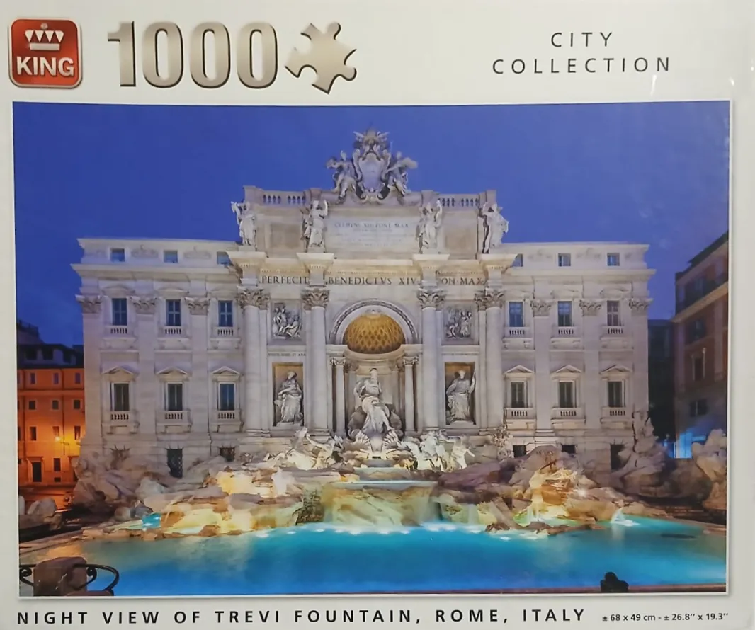 Night view of the illuminated Trevi Fountain in Rome with ornate sculptures and turquoise water.