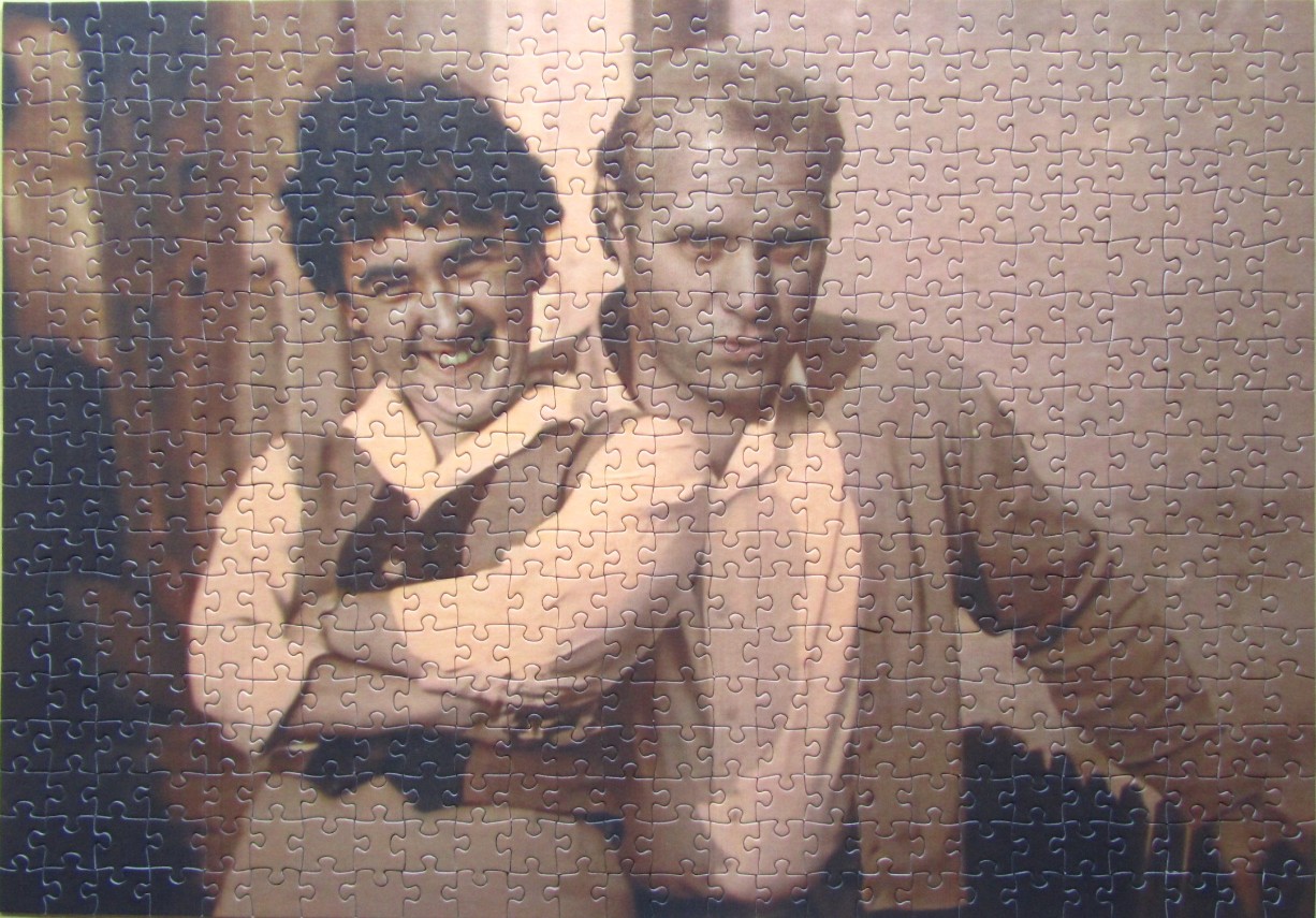A vintage, sepia-toned portrait of two men, one smiling and one looking serious.