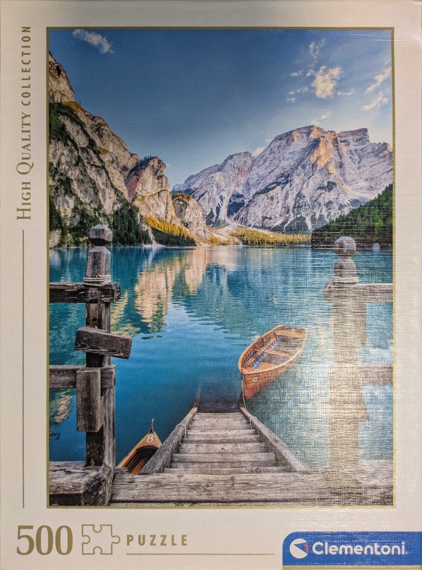 Wooden pier with small rowboats overlooking a tranquil blue lake surrounded by mountains