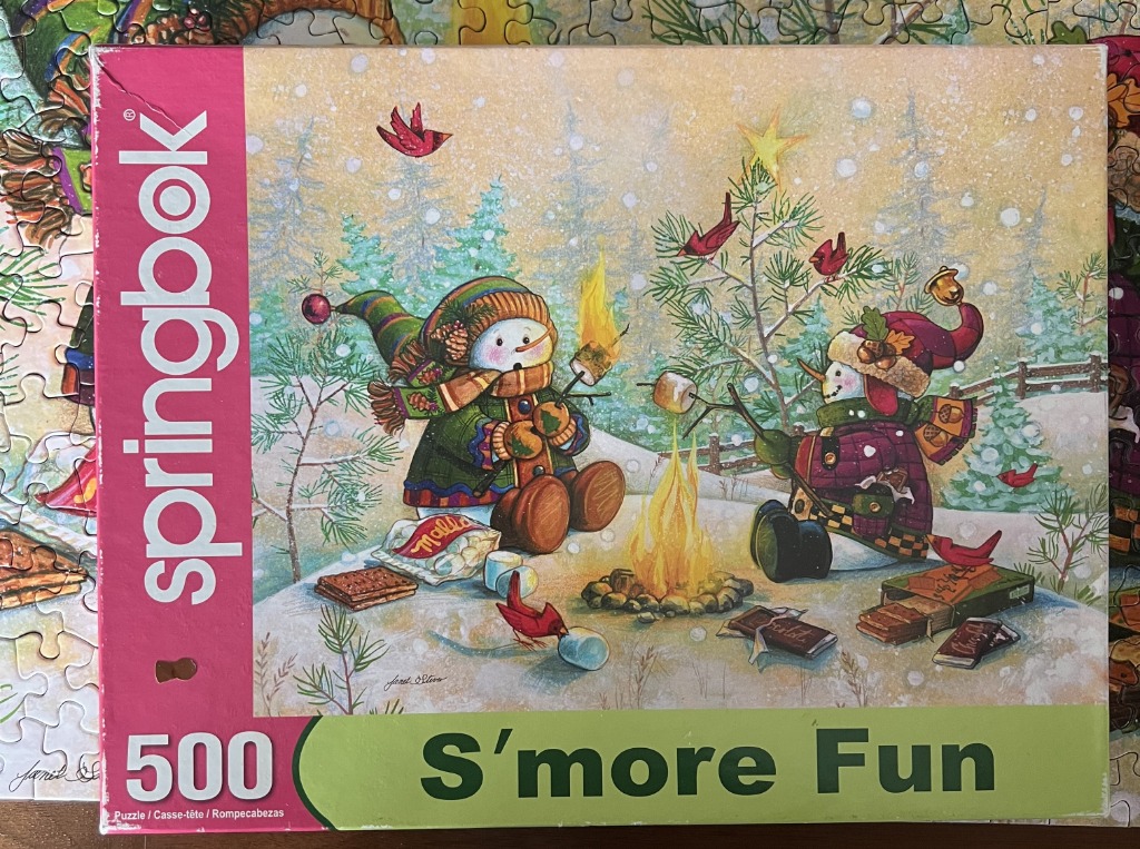Two cartoon snowmen roasting marshmallows over a campfire in a snowy woodland setting.