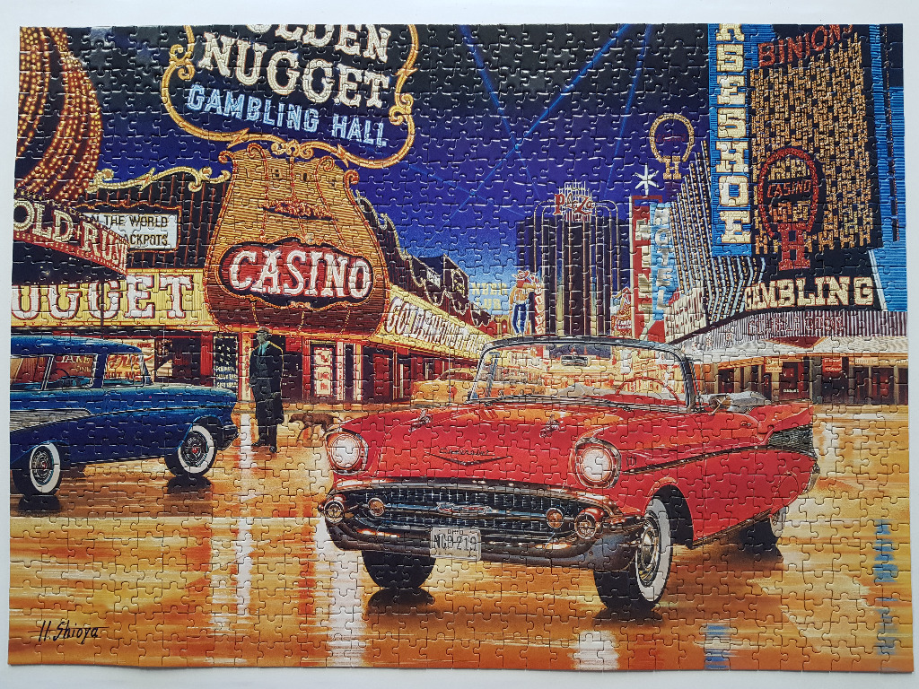 A vintage red convertible parked in front of brightly lit Las Vegas casinos at night.