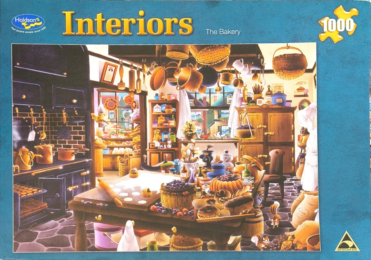 A cozy, rustic bakery interior featuring a large wooden work table filled with baking ingredients and goods.