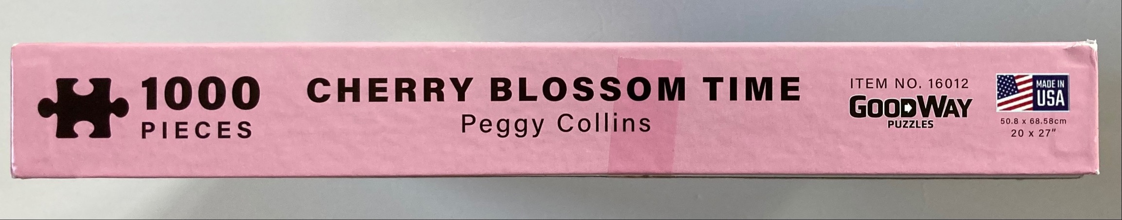 Text on a pink background reading 1000 PIECES, CHERRY BLOSSOM TIME, Peggy Collins, item number 16012, and MADE IN USA.