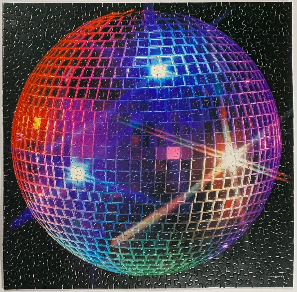 A vibrant disco ball reflecting colorful lights against a dark black background.