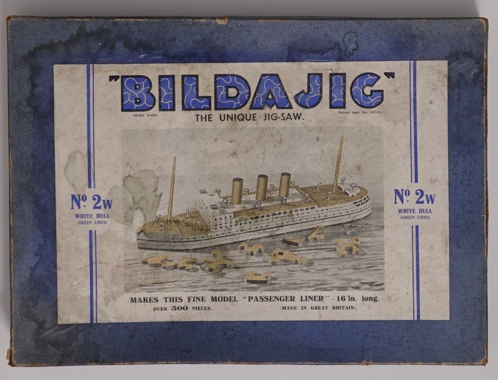 Vintage illustration of a model passenger liner ship with loose puzzle pieces on a wooden surface.