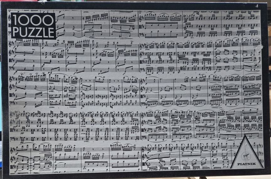A sheet music score printed on a light grey background, featuring various musical staves and notes.